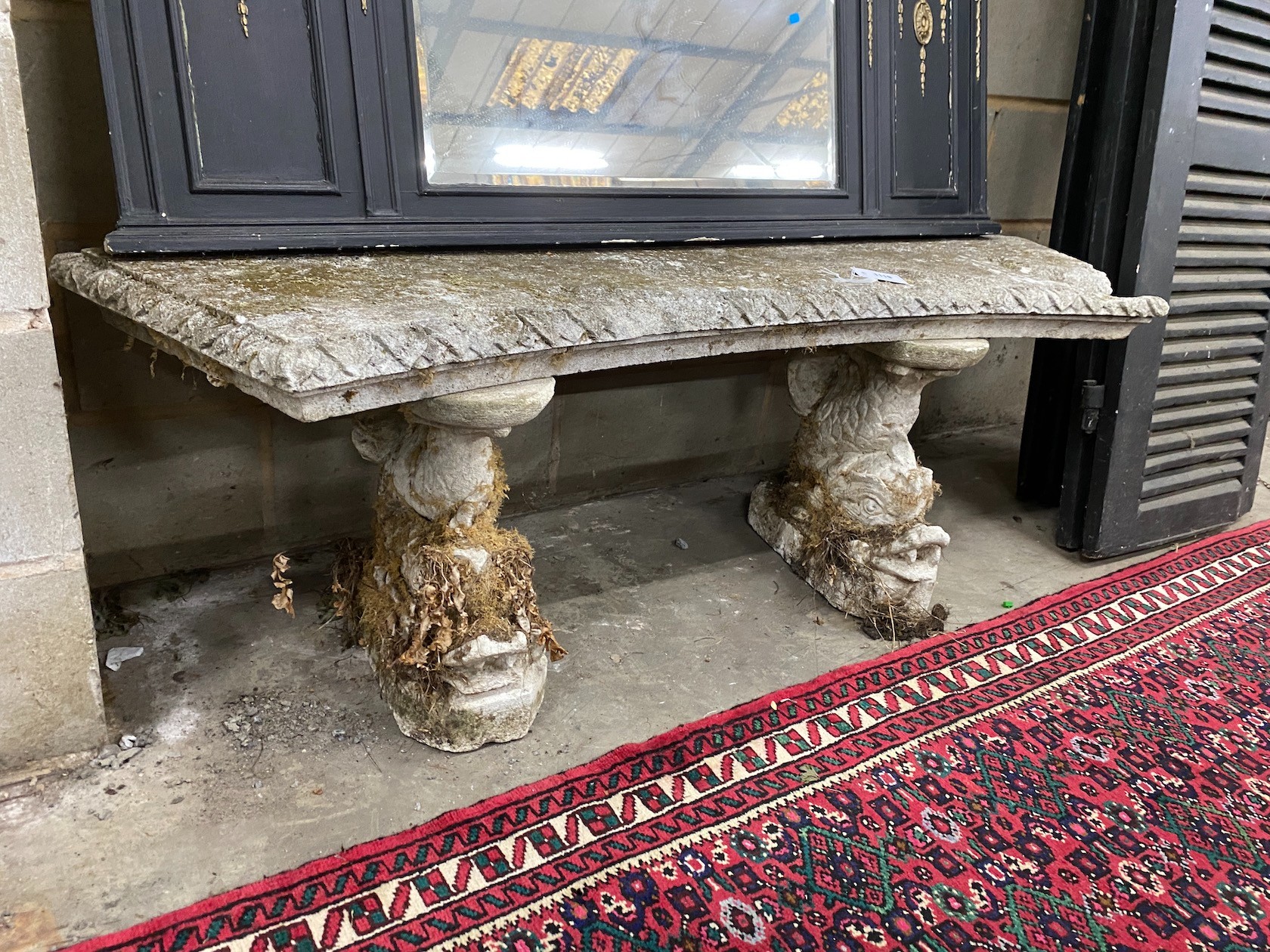 A reconstituted stone curved garden seat on dolphin supports, length 144cm, depth 33cm, height 49cm, Provenance- the late Maureen Marchioness of Dufferin and Ava, Owl House Gardens, Lamberhurst, Kent